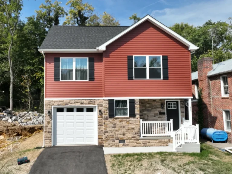 Front exterior view of a custom-built red home with a grey roof