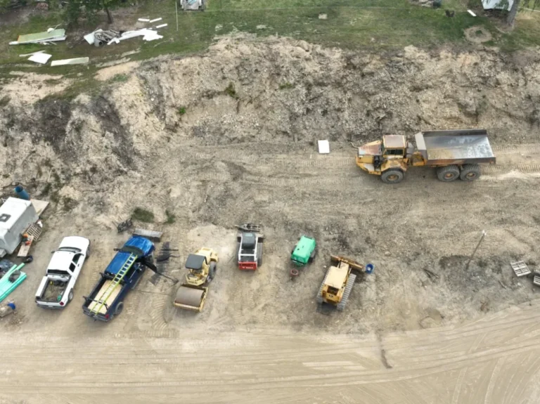Excavation site with heavy equipment and vehicles including rollers, excavators, and hauling trucks